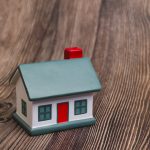 A small, multicoloured house stress reliever in green, white, and red against a wooden background.