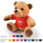 A fluffy tan teddy bear wearing a red T-shirt, sitting upright against a white background. Includes branding on the shirt.