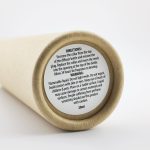 A cylindrical container with a natural beige surface, featuring a label with instructions and warnings.