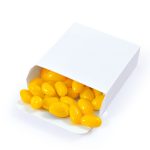 A white box filled with yellow jelly beans, some spilling out of the open packaging.