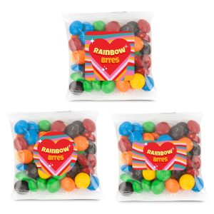 Three clear cello bags containing colorful chocolate-coated candies in various hues, including red, green, blue, and yellow.