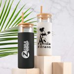 A set of two glass tumblers with bamboo lids, one black and one white, featuring logos and designs.