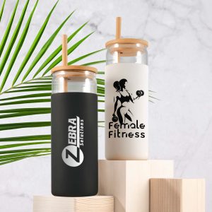 A set of two glass tumblers with bamboo lids, one black and one white, featuring logos and designs.