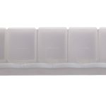 A weekly pill box in translucent white plastic with compartments labeled for each day of the week.