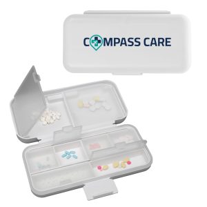 A white compact pill organiser with multiple compartments, featuring a logo on the lid and various coloured pills inside.