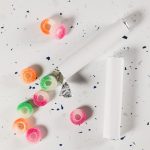 Assorted fruit-flavored gummy rings in various colors, scattered around a partially opened roll.