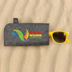 A gray sunglasses case featuring the logo of Faldon Wilson Services, with a pair of yellow sunglasses resting on top.