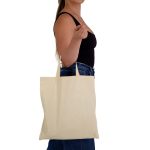 A model holds a beige calico tote bag with short handles, featuring a simple design.