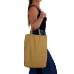 A person holds a mustard yellow tote bag with short handles, featuring a simple design.