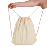 A cream drawstring backpack with a cinched opening, held by a hand. It features a simple design and a logo.
