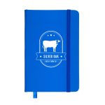 A blue notebook with a cow graphic and an elastic band closure. It features a logo and decorative elements.