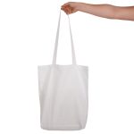 A white cotton long handle bag being held by a hand, featuring two sturdy handles and no visible logos.
