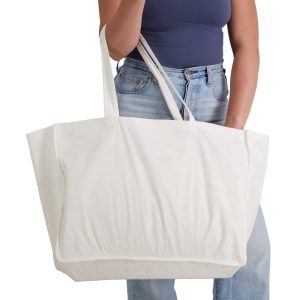 A woman holds a large white reusable grocery bag with two long handles. It appears spacious and made of bamboo fabric.