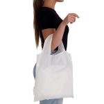 A white reusable shopping bag is held by a person, displaying a simple design and shoulder straps.