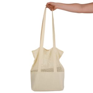 A hand holds a cream-coloured mesh tote bag with long straps, featuring a textured design.