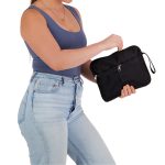 A black utility pouch with a zippered compartment and a wrist strap, held in a woman's hand.