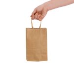 A small brown paper bag with gold handles, held by a hand. The bag has a smooth texture.