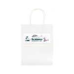 A medium white paper bag with a design featuring a parasol, palm trees, and a flamingo. It has a logo on the front.