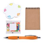 An orange pen, a notepad, colorful sticky notes, and a bag of assorted jelly beans in a gift set.