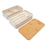A Stax Eco Lunch Box in beige with a bamboo lid and utensils, featuring a divided interior for organisation.