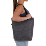 A grey RPET tote bag with a gusset, featuring a logo, held by a person from the side.