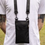A black neck pouch with a zipper pocket and adjustable straps, worn on the back of a person.