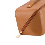 A tan toiletry bag with a gold zipper, featuring a sleek design and a branding logo.