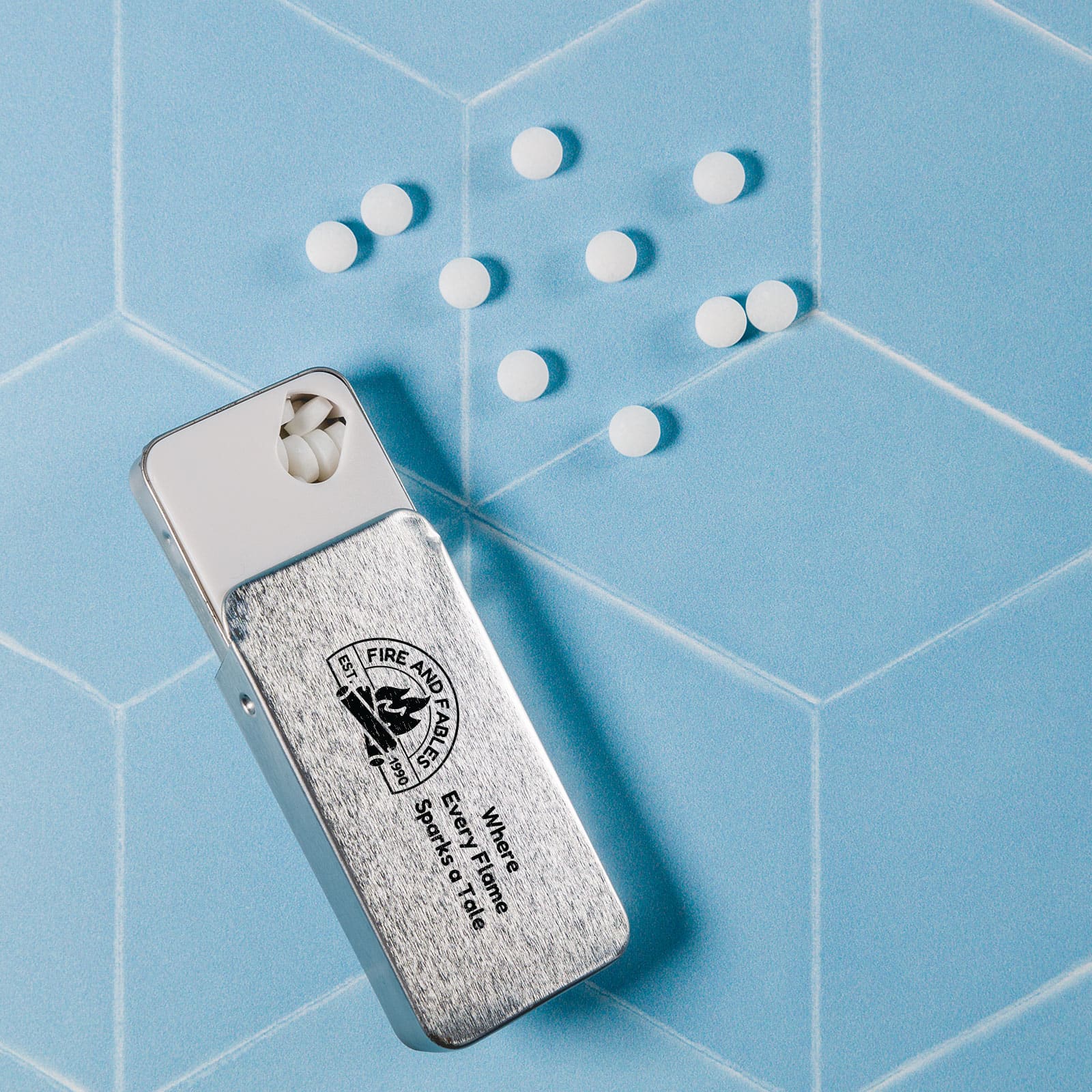 A silver slider tin containing sugar-free breath mints, with white mints scattered beside it on a pastel blue background.