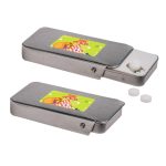 A silver slider tin filled with sugar-free breath mints, featuring a colorful label and two mints beside it.