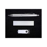 A silver pen, a silver USB drive, and a silver cardholder arranged on a black surface.