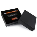 A black gift box containing an orange pen, a black USB drive, and a stylish black card holder.