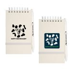 A notepad with a cow pattern cover, featuring a white pen attached, in light and dark colors.