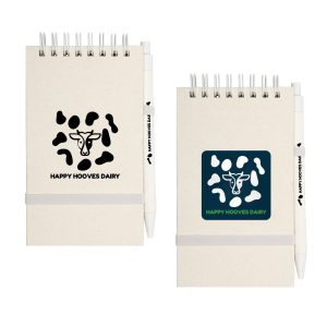 A notepad with a cow pattern cover, featuring a white pen attached, in light and dark colors.