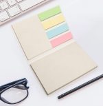 A sticky note booklet featuring various colored sticky notes in a compact design, accompanied by a pen and glasses.