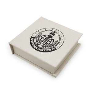 A square gift box in a light cream colour, featuring a logo on the lid.
