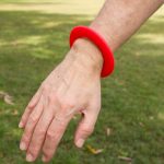 A bright red silicone flyer designed for outdoor play, worn on a wrist.