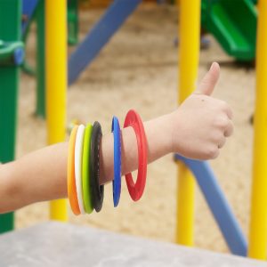 A wrist adorned with colorful silicone flyers, including red, orange, green, black, yellow, and blue discs.