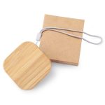 A square bamboo cable organiser with a silver strap, alongside a kraft paper packaging box.