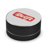 A round black Bluetooth speaker with a silver rim and a white top featuring a logo.