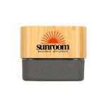 A Bluetooth speaker featuring a bamboo exterior and a grey base, with a logo displayed on the front.