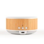 A round speaker and wireless charger in natural wood and white, featuring control buttons and a USB-C port.