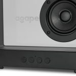 A speaker with a white front and dark grey base, featuring a circular speaker grille and control buttons.