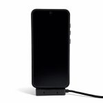A black smartphone set on a stand with a charging cable connected, featuring a logo on the cable.