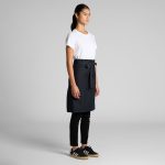 A dark navy half apron with a waist tie, worn over a white t-shirt and black pants.