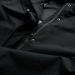A soft shell jacket in black, featuring a zip and snap closures, with a textured interior lining.
