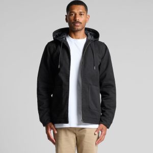 A man wearing a black canvas heavy hooded jacket with zip and front pockets. The jacket has a hood and a grey lining.